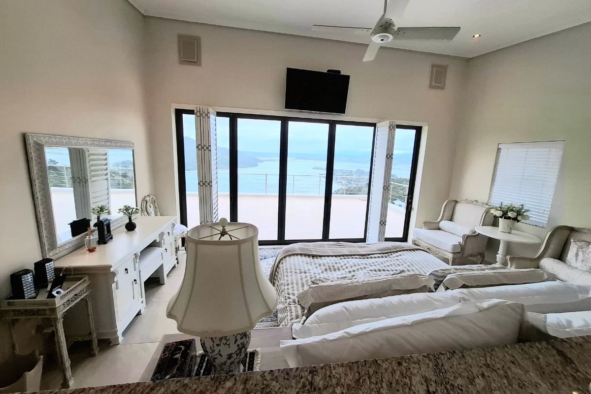 Spacious bedroom featuring tiled flooring, a ceiling fan, and large sliding glass doors that open onto a balcony with scenic water views.