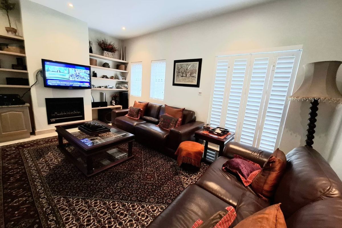 A comfortable living room featuring built-in shelving, a gas fireplace, and plantation shutters, providing a warm and inviting atmosphere.