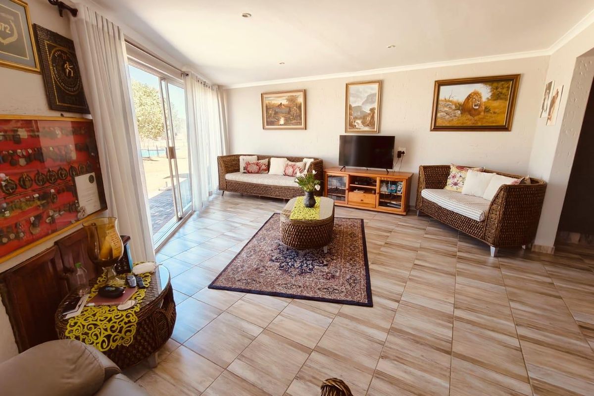Spacious living room featuring large sliding glass doors that provide natural light and direct access to the outdoor area, complemented by neutral tiled flooring.