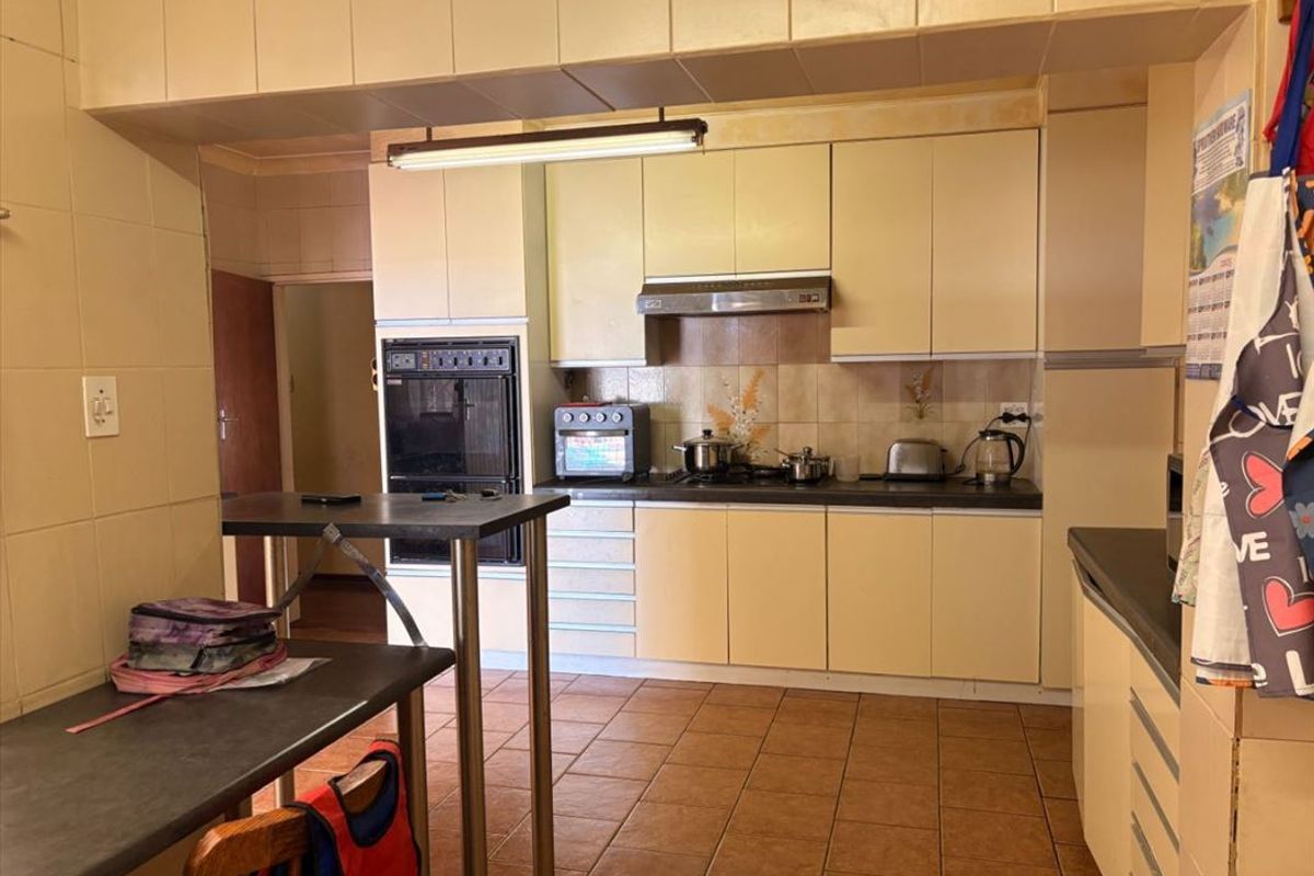 A functional kitchen featuring built-in cabinetry, an integrated oven, extractor fan, and tiled flooring, offering a classic layout with potential for modern updates.