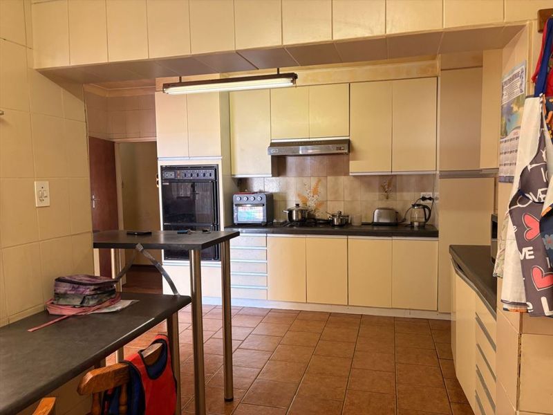 A functional kitchen featuring built-in cabinetry, an integrated oven, extractor fan, and tiled flooring, offering a classic layout with potential for modern updates.