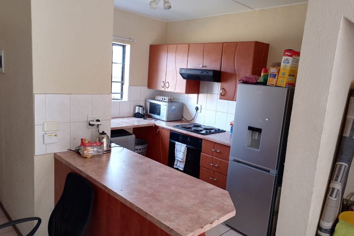 A functional kitchen featuring laminate cabinetry, built-in oven with hob, extractor fan, and a breakfast bar counter.