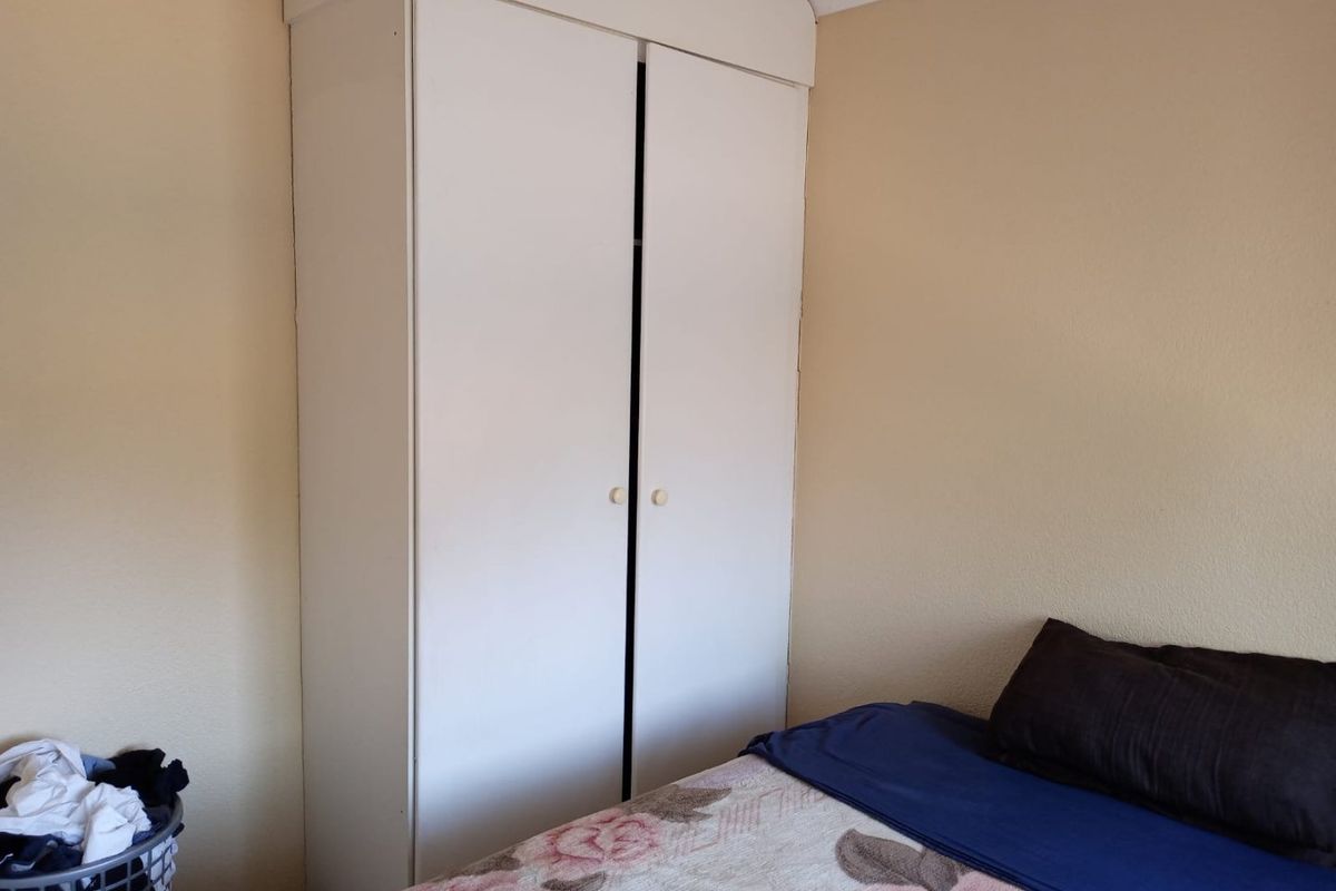 A bedroom featuring a standard white built-in wardrobe with simple cabinetry.