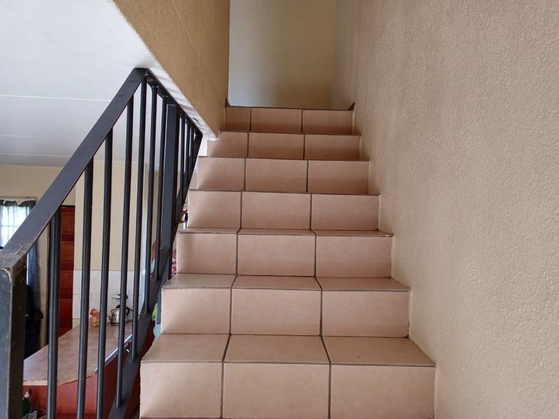 A functional staircase featuring tiled steps and a simple metal balustrade, providing access between levels in this townhouse.