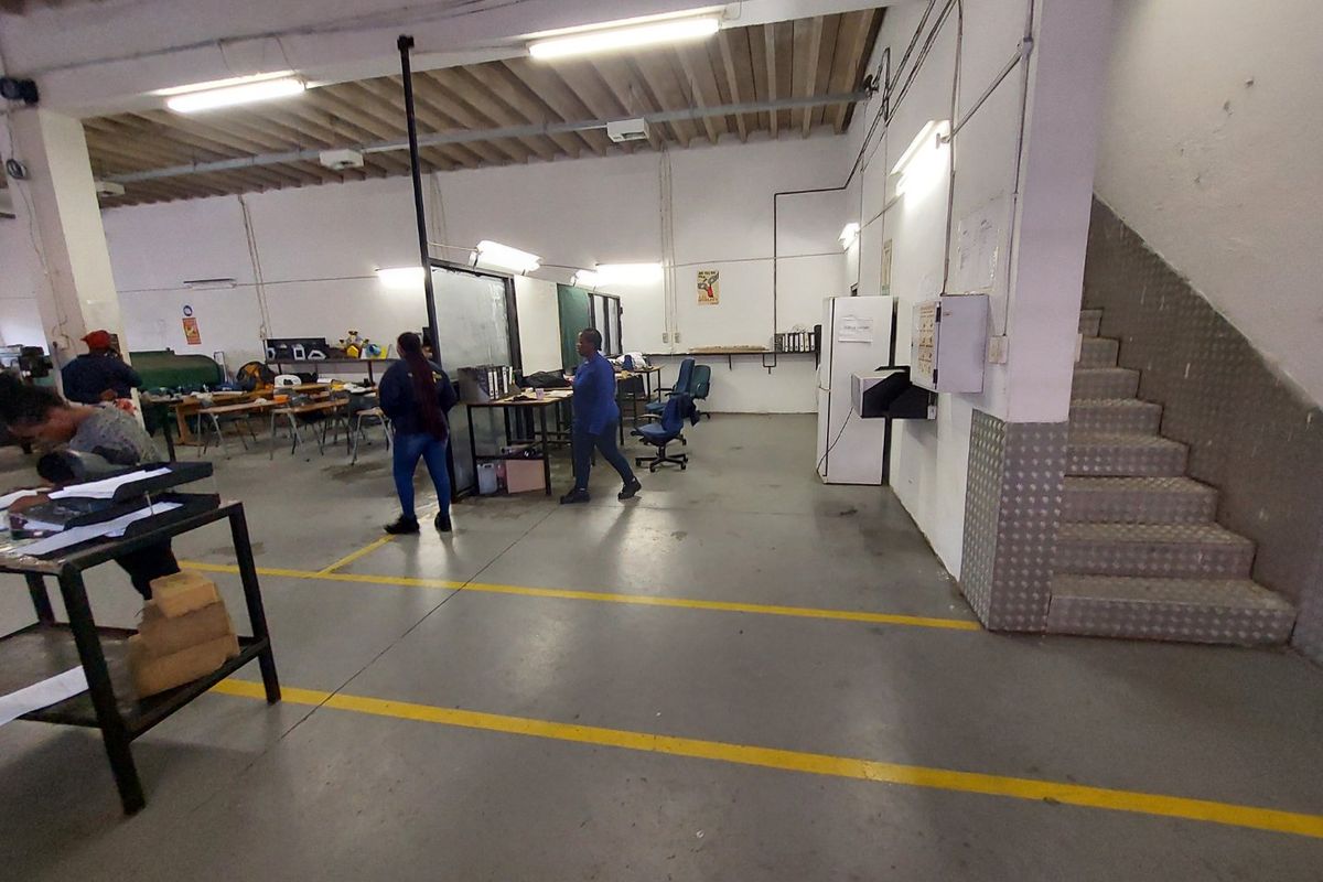 Spacious industrial utility area featuring exposed ceiling beams, concrete flooring, and a metal-tread staircase, suitable for workshop or storage operations.