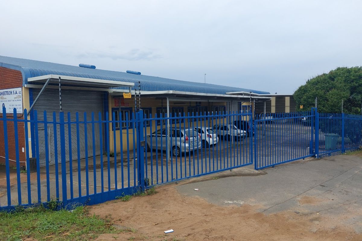 Industrial property featuring a corrugated metal roof, secure roller shutter access, and perimeter steel palisade fencing with electric security wires.