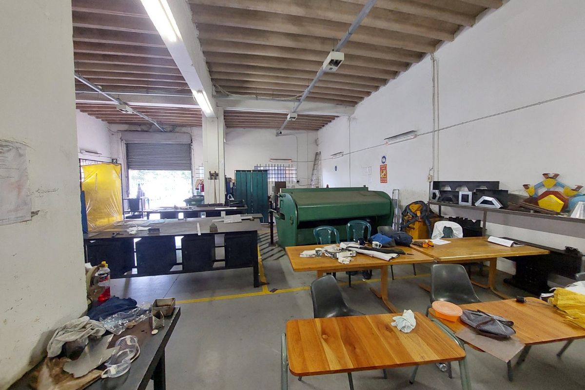 Industrial utility space featuring high exposed beam ceilings, concrete flooring, and a large roller shutter door for easy access.