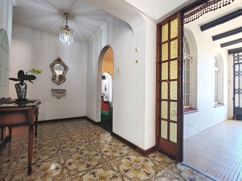 A character-filled entrance hall featuring decorative patterned floor tiles, an arched transition, and a classic leaded glass timber door leading to a side patio.