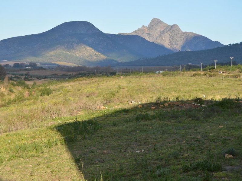 Expansive rural landscape view featuring rolling fields and prominent mountain ranges in the distance.
