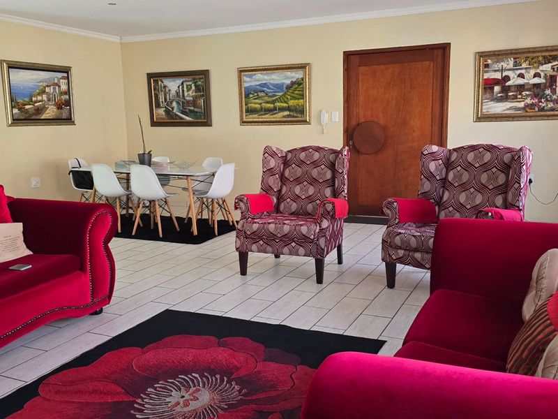 Spacious open-plan living and dining area featuring neutral wall tones, tiled flooring, and a solid timber entrance door.