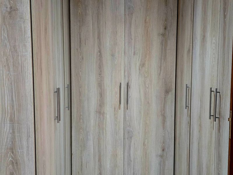 A close-up view of modern, light wood-grain built-in cupboards with sleek metal handles, providing ample storage space.