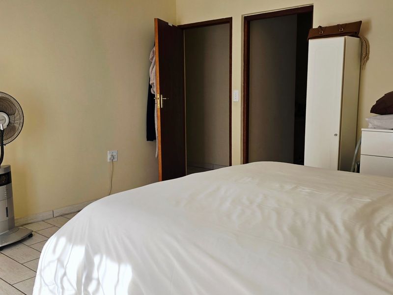 A functional bedroom featuring tiled flooring and dual internal access doors, providing a neutral base for interior design updates.