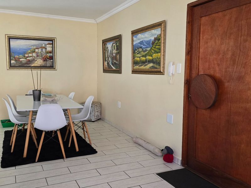 A bright dining area featuring tiled flooring, coving, and a prominent solid wood entrance door with an integrated intercom system.