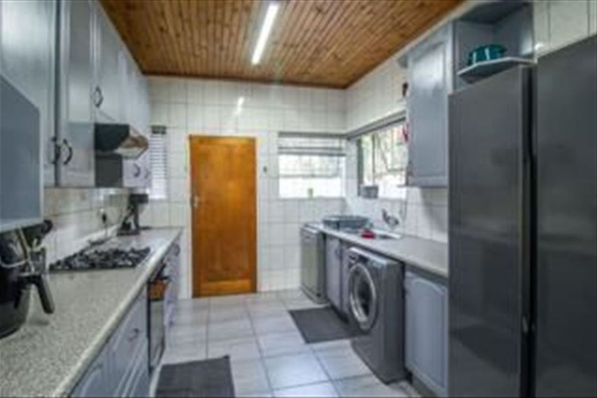 Functional kitchen featuring built-in cabinetry, gas hob, extractor fan, and tiled finishes with a timber ceiling.