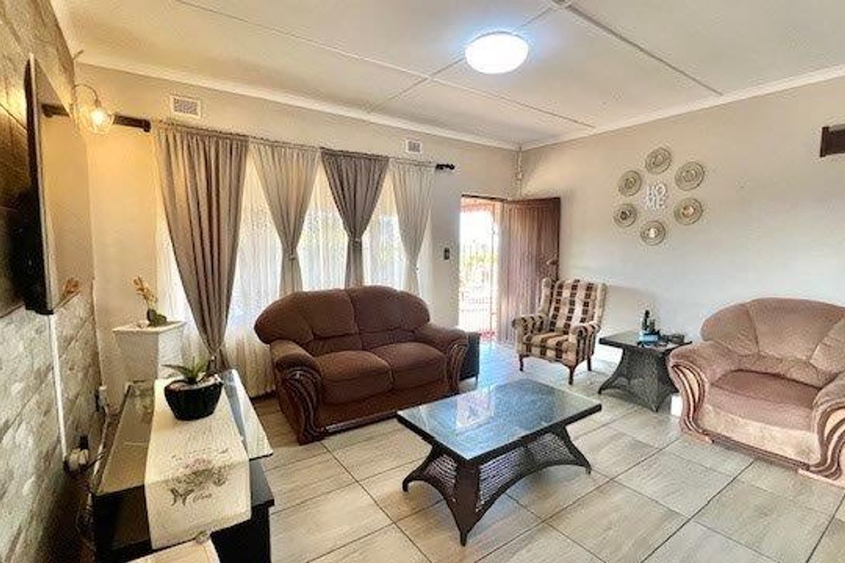 A living room featuring tiled flooring and a stone-cladding feature wall, providing a functional and neutral space for relaxation.