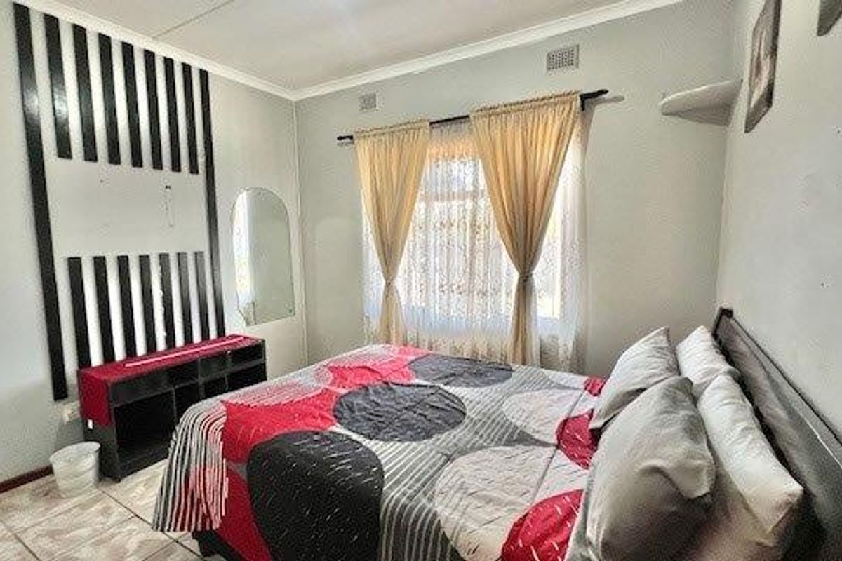 A bedroom featuring tiled flooring, coving, and a decorative wall feature.