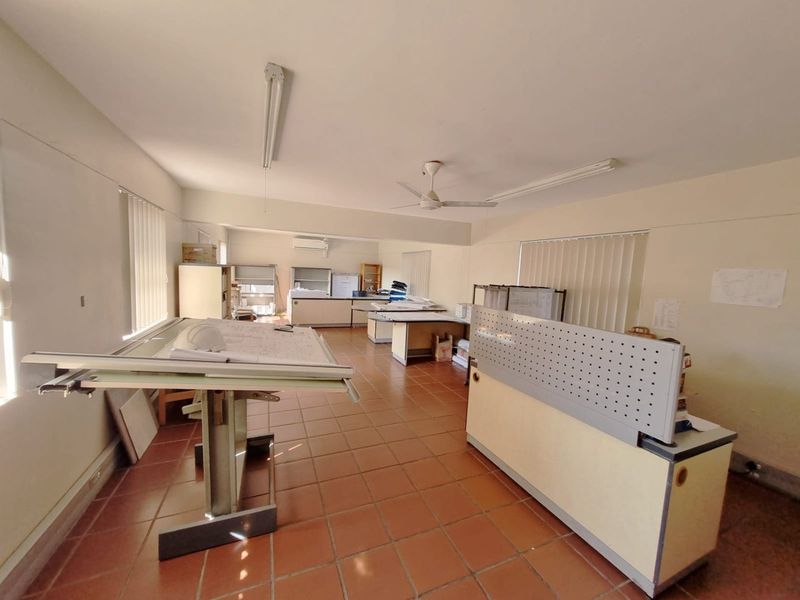 Spacious commercial office area featuring terracotta floor tiles, built-in workstations, vertical blinds, and integrated climate control systems.