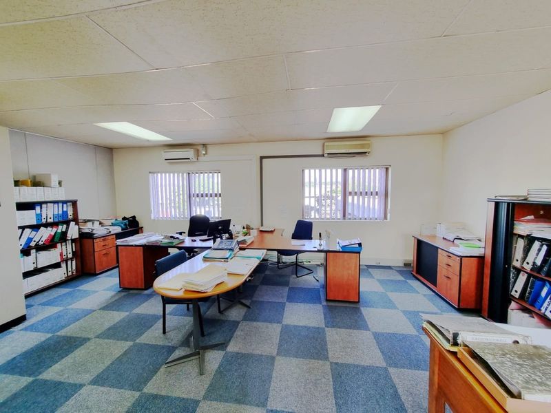 A functional commercial office space featuring suspended ceilings, recessed lighting, split-system air conditioning, and durable carpet tiles.