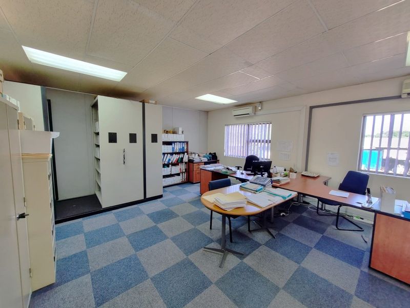 Functional commercial office space featuring suspended ceilings, recessed lighting, split-system air conditioning, and security-barred windows with carpet tile flooring.