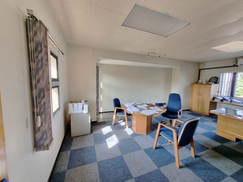 A functional commercial office space featuring carpet tile flooring, recessed ceiling lighting, and built-in storage cabinetry.