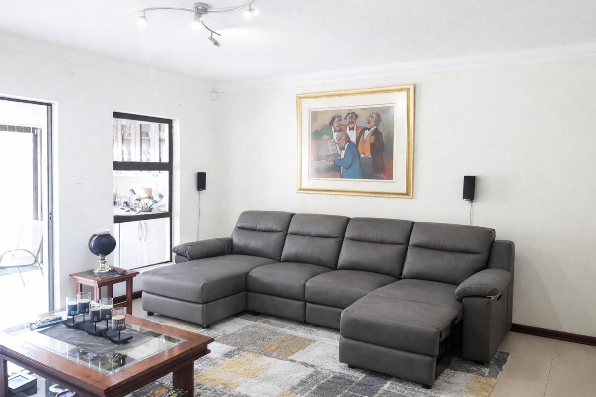 A well-maintained living room featuring tiled flooring, coved ceiling cornices, and a sliding glass door providing natural light and access to the exterior.