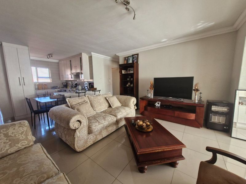 Open-plan living area featuring tiled flooring, coving, and a functional kitchen with built-in cabinetry and an extractor fan.