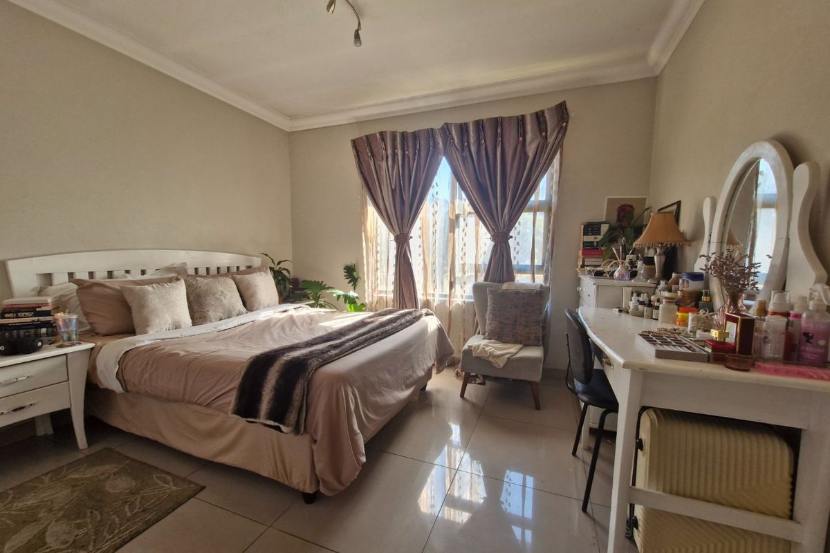 A well-lit bedroom featuring tiled flooring, ceiling coving, and track lighting, offering a comfortable and functional living space.