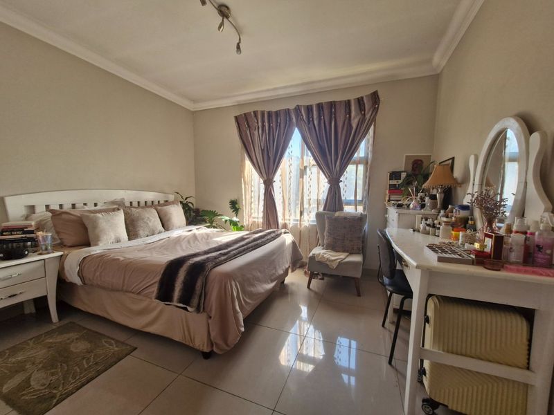 A well-lit bedroom featuring tiled flooring, ceiling coving, and track lighting, offering a comfortable and functional living space.