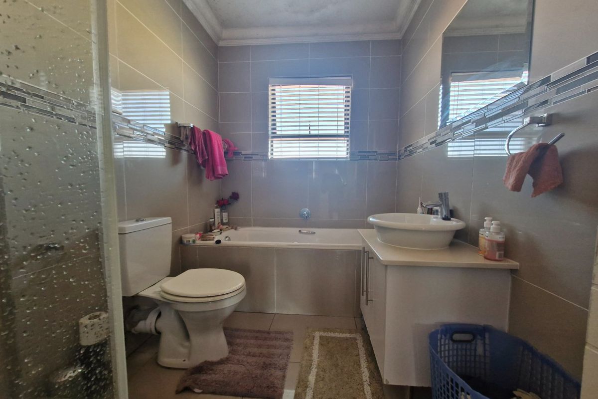 A functional bathroom featuring a built-in bathtub, vessel sink with vanity cabinet, toilet, and a separate shower enclosure with tiled finishes.