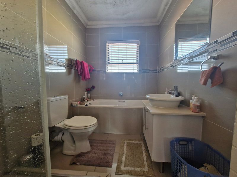 A functional bathroom featuring a built-in bathtub, vessel sink with vanity cabinet, toilet, and a separate shower enclosure with tiled finishes.