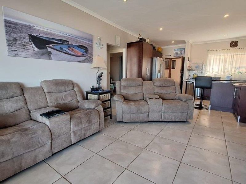 Open-plan living area featuring tiled flooring, recessed lighting, and a functional kitchen with a breakfast bar island.