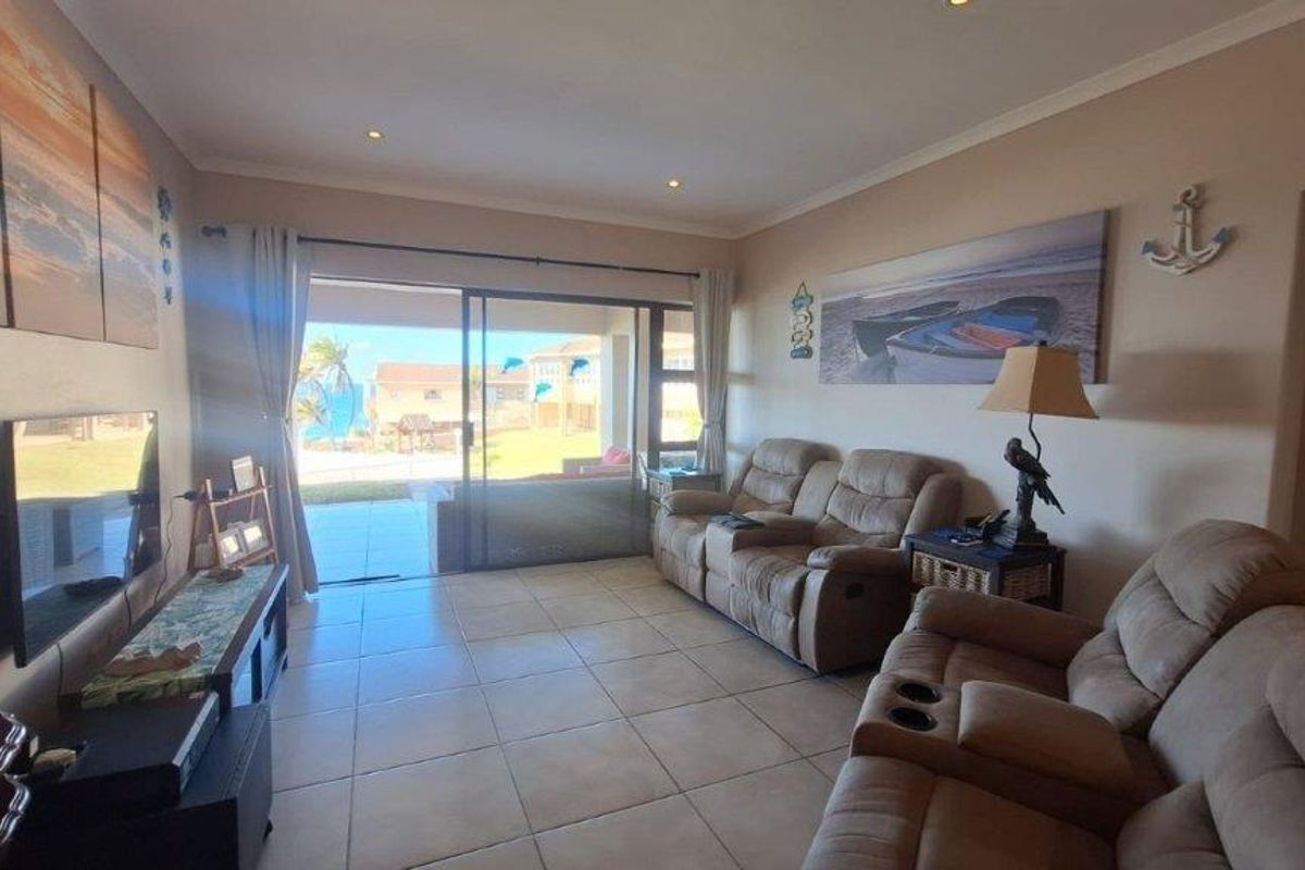 A comfortable living room featuring tiled flooring and a large sliding glass door that provides direct access to an outdoor patio area.