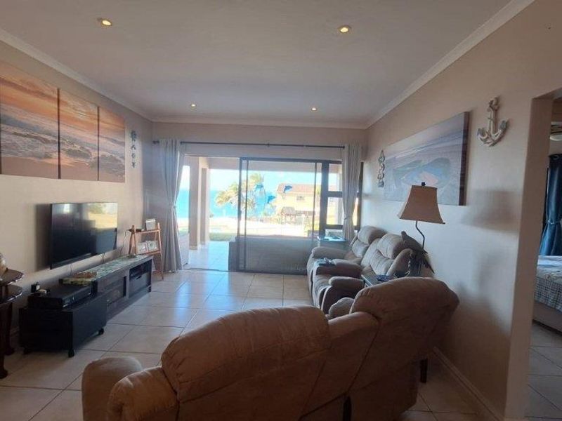Open-plan living area featuring tiled flooring, recessed downlights, and a large sliding glass door providing access to an outdoor patio area.