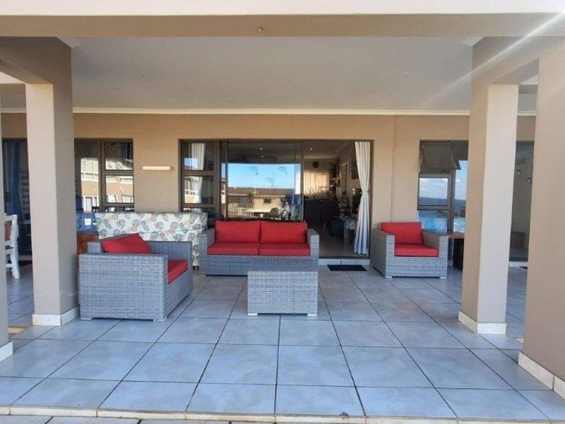 A spacious covered patio featuring tiled flooring and recessed lighting, providing seamless access to the interior living area through large sliding glass doors.