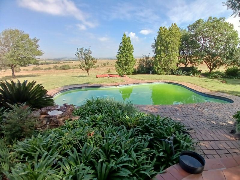 Outdoor pool area featuring brick paving, a rock water feature, and expansive rural landscape views.