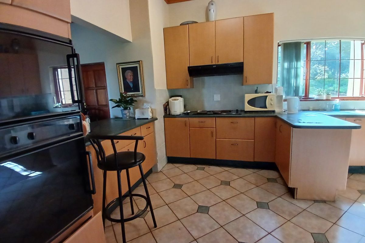 A functional kitchen featuring timber cabinetry, built-in oven, extractor fan, tiled flooring, and a timber ceiling, offering a classic farm-style aesthetic.