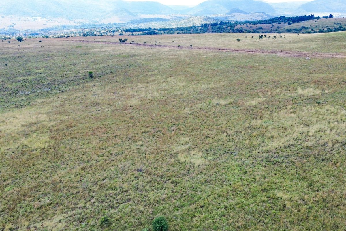 An expansive aerial view of open farm land with rolling hills in the background.