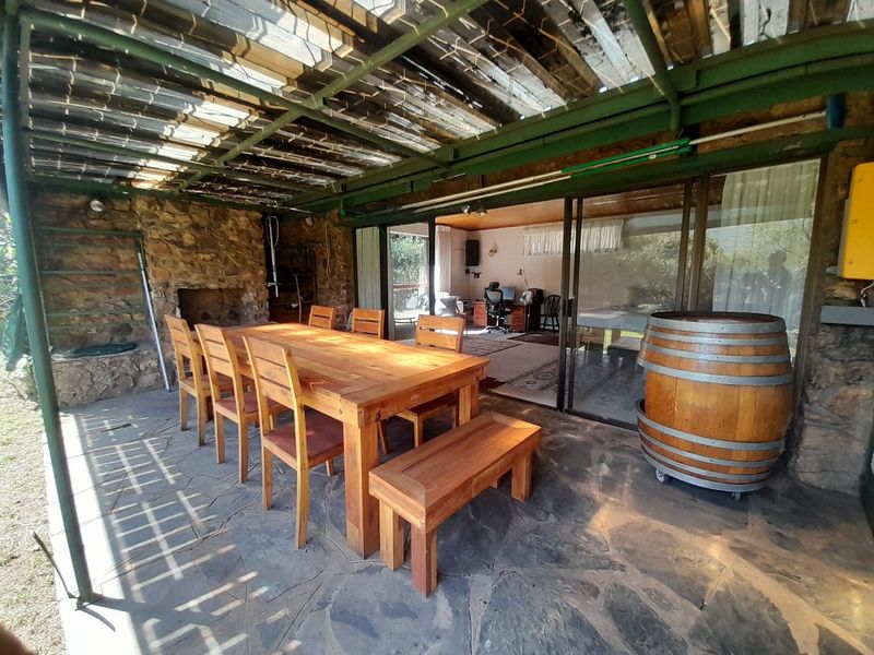 Covered outdoor patio featuring stone flooring, a built-in fireplace, and a metal roof structure, providing direct access to the interior living space.