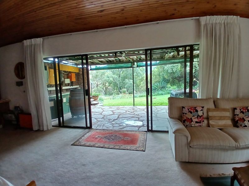 Living room featuring a timber ceiling and large sliding glass doors that open onto a stone patio with garden views.