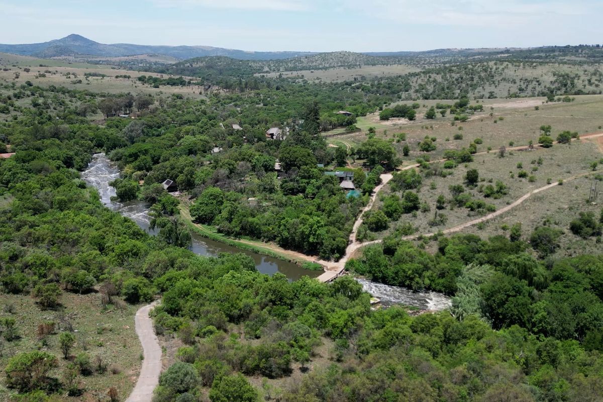 An aerial view of the farm property featuring a river, natural landscape, and access roads.