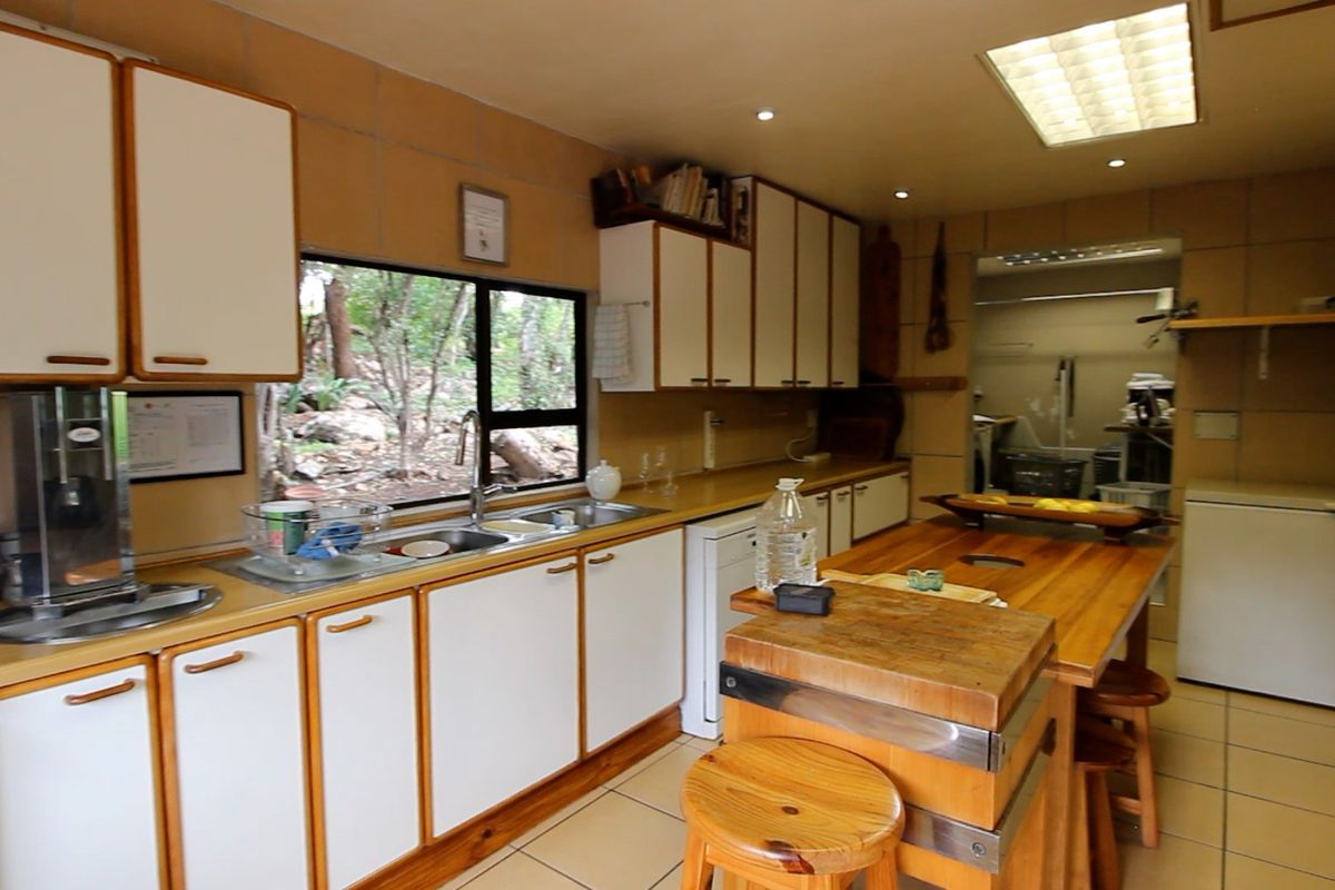 A functional kitchen featuring wooden countertops, ample built-in cabinetry, and a double sink, with a view of the surrounding natural landscape.