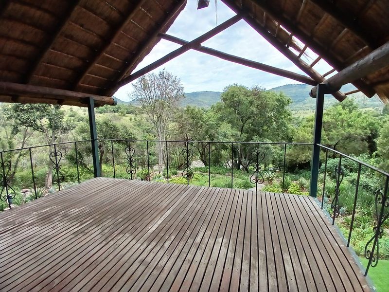 An elevated timber deck featuring a traditional thatched roof and wrought iron balustrade, offering expansive views of the surrounding natural landscape.