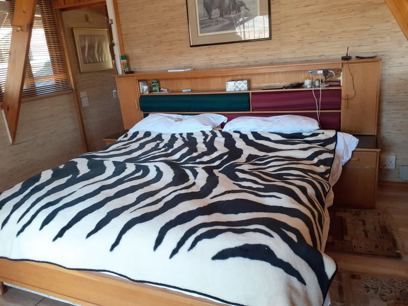 A bedroom featuring wood-paneled walls, a built-in headboard, and a sloped ceiling, reflecting a rustic farm-style aesthetic.