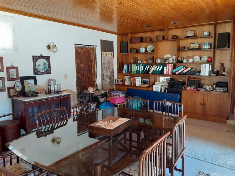 A dining room featuring a large built-in wooden shelving unit and a timber tongue and groove ceiling with recessed lighting.