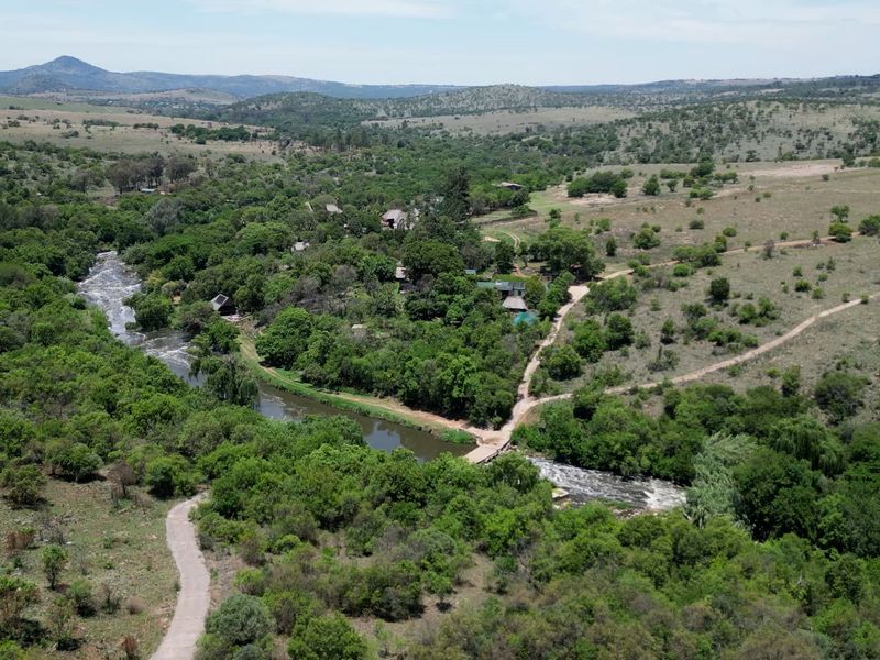 An aerial view of the farm property featuring a river, natural landscape, and access roads.