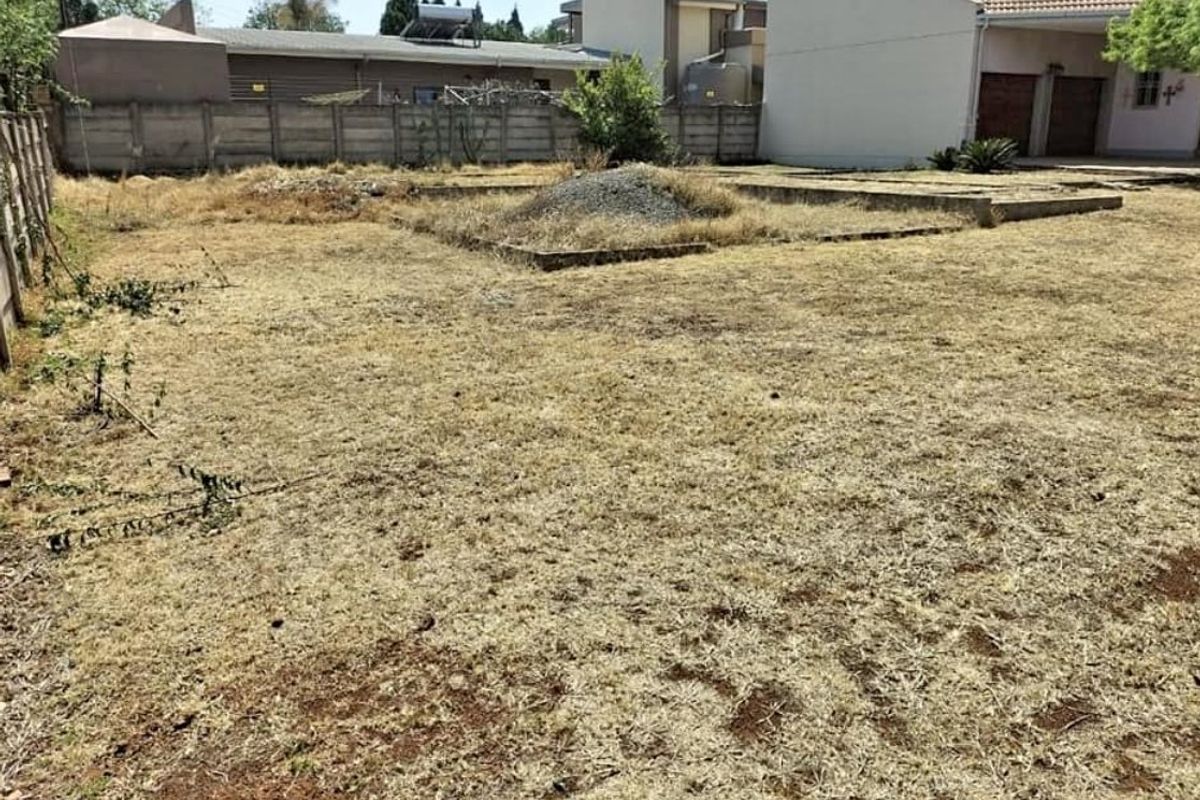 A vacant residential plot featuring a concrete boundary wall and an existing concrete foundation slab, currently requiring landscaping and site clearing.