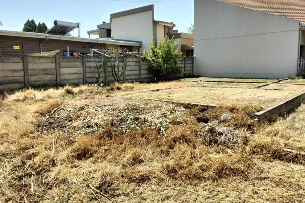 A vacant residential plot featuring a concrete foundation slab and perimeter boundary wall, currently requiring significant landscaping and site clearing.