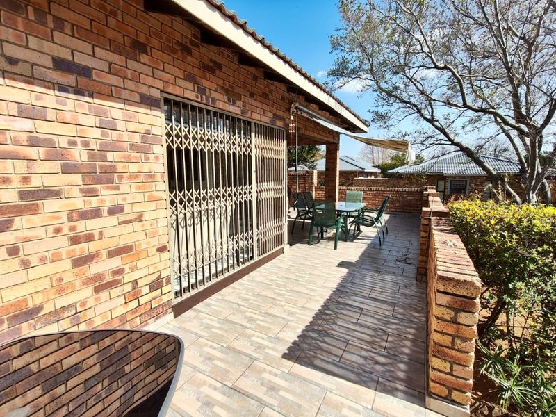 Covered outdoor patio featuring face brick walls, tiled flooring, and a retractable awning, providing a functional space for outdoor dining and relaxation.