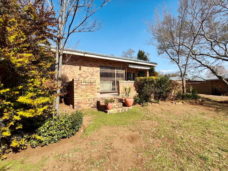 A view of the rear face brick facade of the house, featuring a small patio area with security gate access and surrounding garden space.