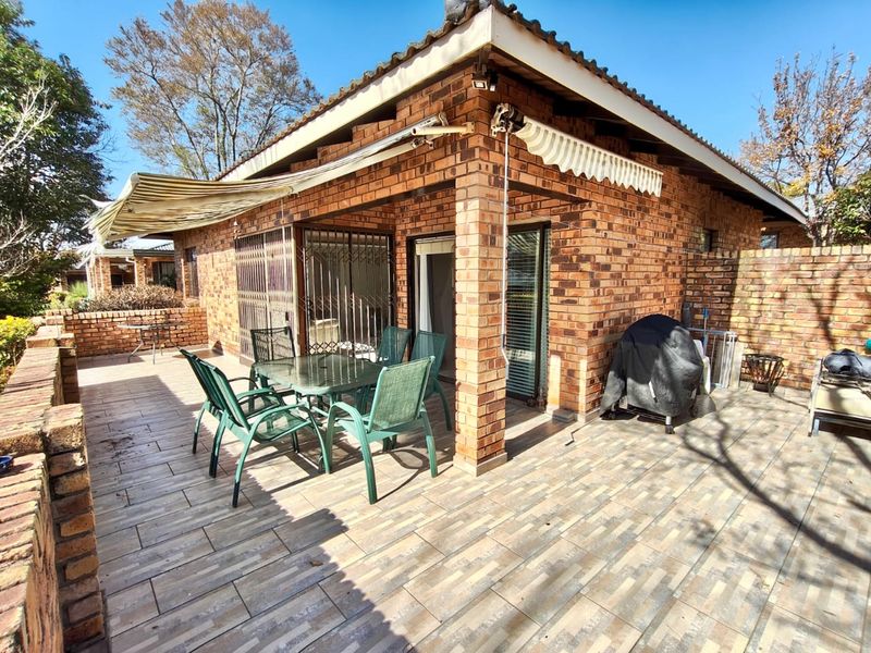 A covered outdoor patio area featuring face brick construction, tiled flooring, and retractable awnings, providing a functional space for outdoor living and entertainment.